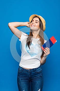 Portrait of a happy smiling young girl holding passport and travelling tickets isolated over blue background