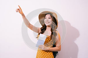 Portrait of a happy smiling young girl holding passport and travelling tickets isolated over pastel background