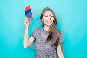 Portrait of a happy smiling young girl holding passport and travelling tickets over blue background