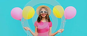 Portrait happy smiling young woman with bunch of colorful balloons on a blue background