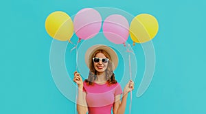 Portrait happy smiling young woman with bunch of colorful balloons on a blue background