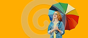 Portrait of happy smiling young woman with colorful umbrella isolated on yellow background, blank copy space for advertising text