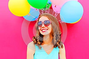 Portrait happy smiling young woman having fun over an air colorful balloons pink