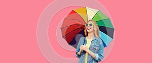 Portrait of happy smiling young woman with multicolored colorful umbrella isolated on pink background, blank copy space for