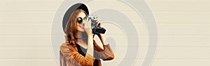 Portrait of happy smiling young woman photographer with film camera on gray background