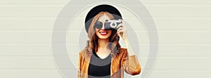 Portrait of happy smiling young woman photographer with film camera on gray background