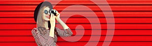 Portrait of happy smiling young woman photographer with film camera on red background