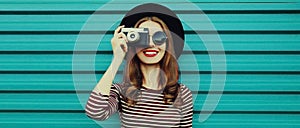 Portrait happy smiling young woman photographer with vintage film camera on colorful blue background
