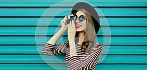 Portrait happy smiling young woman photographer with vintage film camera on colorful blue background