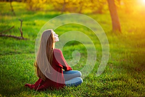 Portrait of happy sporty woman relaxing in park on green meadow. Joyful female model breathing fresh air outdoors