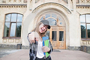Portrait of a happy student with books and notebooks in the hands of the university building background