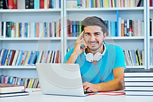 Portrait of happy student while reading book in school library.