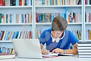 Portrait of happy student while reading book in school library.