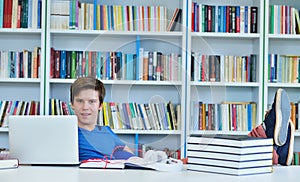 Portrait of happy student while reading book in school library.