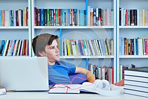 Portrait of happy student while reading book in school library.