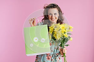 Portrait of happy stylish female in floral dress on pink