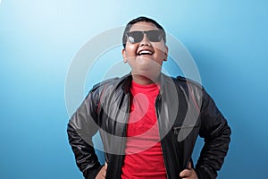 Happy success fat Asian boy wearing leather jacket and sunglasses shows winning gesture