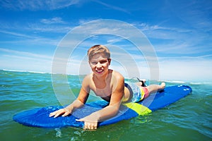 Portrait of happy surfing boy lay on surfboard