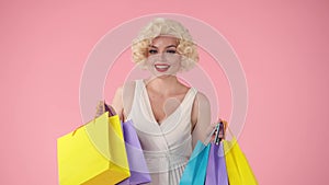 Portrait of a happy surprised woman with colorful shopping bags. Woman in the image of Marilyn Monroe opens one of the