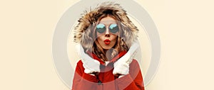 Portrait of happy surprised young woman wearing red jacket with fur hood and mittens