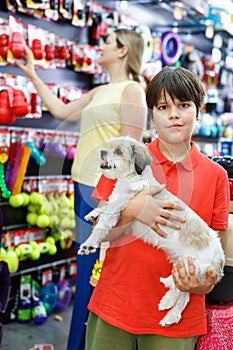 Portrait of happy teen boy with his little dog visiting pet supplies shop with mother