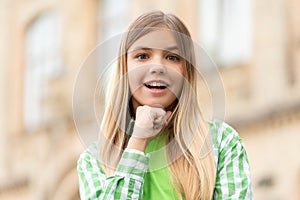 Portrait of happy teen girl smiling with chin on hand blurry outdoors