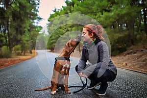 Portrait of happy teenage girl and Rhodesian ridgeback dog . Dog giving girl sweet kiss lick.