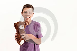 Portrait of happy teenaged disabled boy with cerebral palsy smiling at camera and holding his teddy bear toy, posing