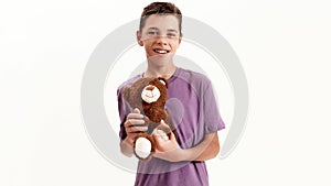 Portrait of happy teenaged disabled boy with cerebral palsy smiling at camera and holding his teddy bear toy, posing