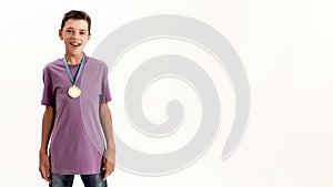 Portrait of happy teenaged disabled boy with cerebral palsy wearing gold medal, smiling at camera while standing