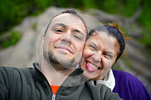 Portrait of happy tourist couple taking selfie in forest