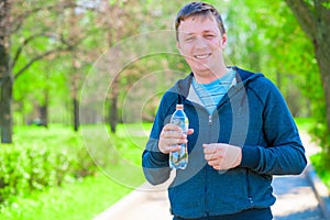 Portrait of a happy trainer with a bottle of water