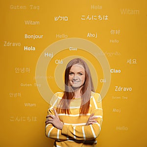Portrait of happy translator and greeting words in different foreign languages on orange background