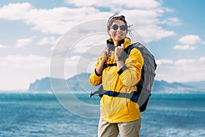 Portrait of a happy traveler tourist on the background of the sea. Portrait of a young woman in tourist gear.