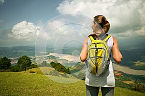 Portrait of happy traveler woman with backpack standing on top o