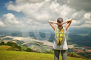 Portrait of happy traveler woman with backpack standing on top o