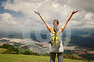 Portrait of happy traveler woman with backpack standing on top o