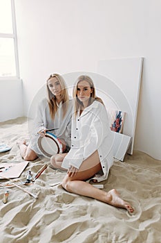 Portrait of happy twin girls artists. Sister girls in a photo studio on the sand.