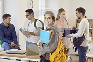 Portrait of happy university or college student holding her notebook and smiling