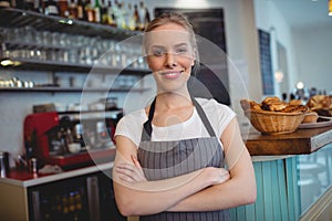 Portrait of happy waitress with arms crossed at cafe