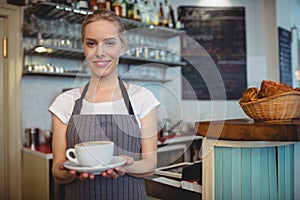 Portrait of happy waitress serving beverage at cafe