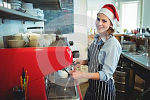 Portrait of happy waitress wearing Santa hat at cafe