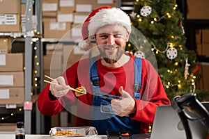 Portrait of happy warehouse worker eating sushi from lunch break delivery showing thumbs up class gesture.