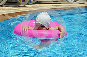 Portrait of happy white Caucasian child baby girl toddler in swimming pool outdoor. Preschool boy training to float with