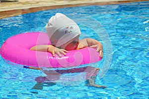 Portrait of happy white Caucasian child baby girl toddler in swimming pool outdoor. Preschool boy training to float with