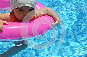 Portrait of happy white Caucasian child baby girl toddler in swimming pool outdoor. Preschool boy training to float with