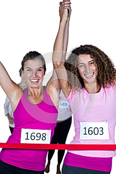 Portrait of happy winner athletes crossing finish line with arms raised