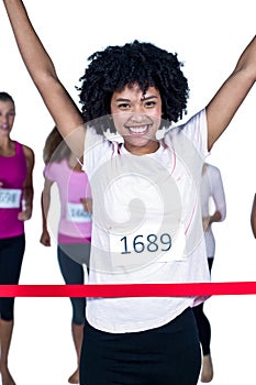 Portrait of happy winner female athlete crossing finish line with arms raised