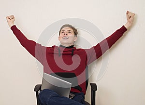 Portrait of a happy winning  young teenager boy using laptop and celebrating success isolated over white wall