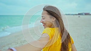 Portrait happy woman with blowing hair having fun on beach, holding someone hand